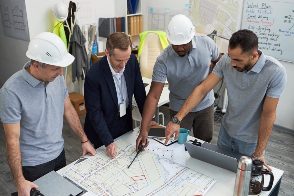 Equipa de profissionais a analisar plantas de um projeto de engenharia.