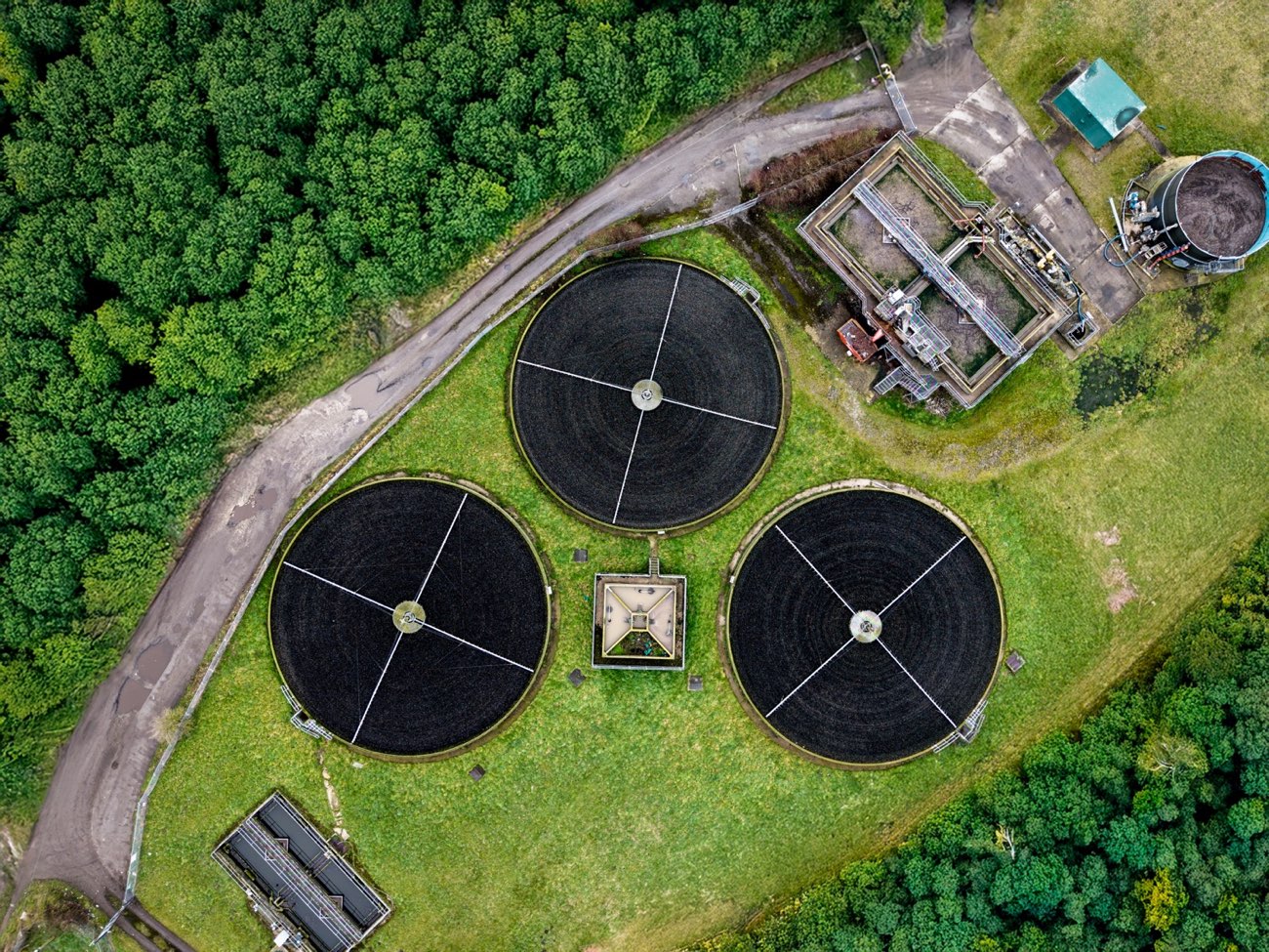 Vista aérea de uma estação de tratamento de águas residuais rodeada por floresta